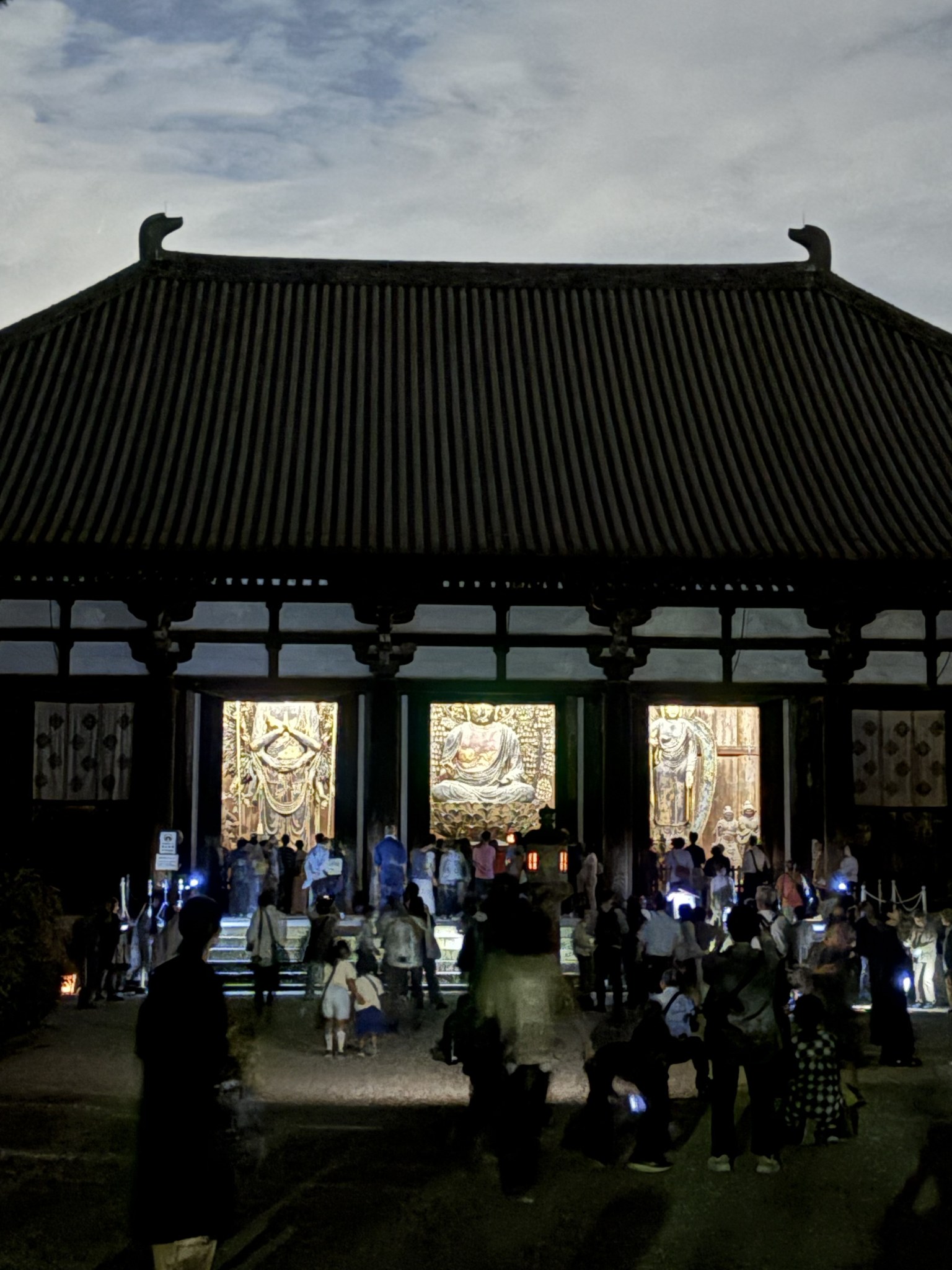 夜空を背にした唐招提寺金堂の寄棟の屋根と開かれた扉