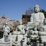 大きな石仏の足もとに並ぶ文殊菩薩や普賢菩薩などの石像と三重塔