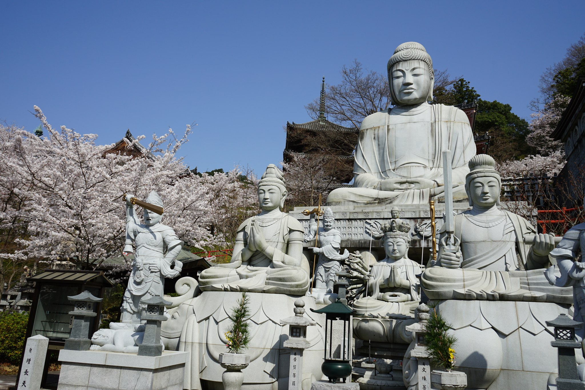 大きな石仏の足もとに並ぶ文殊菩薩や普賢菩薩などの石像と三重塔