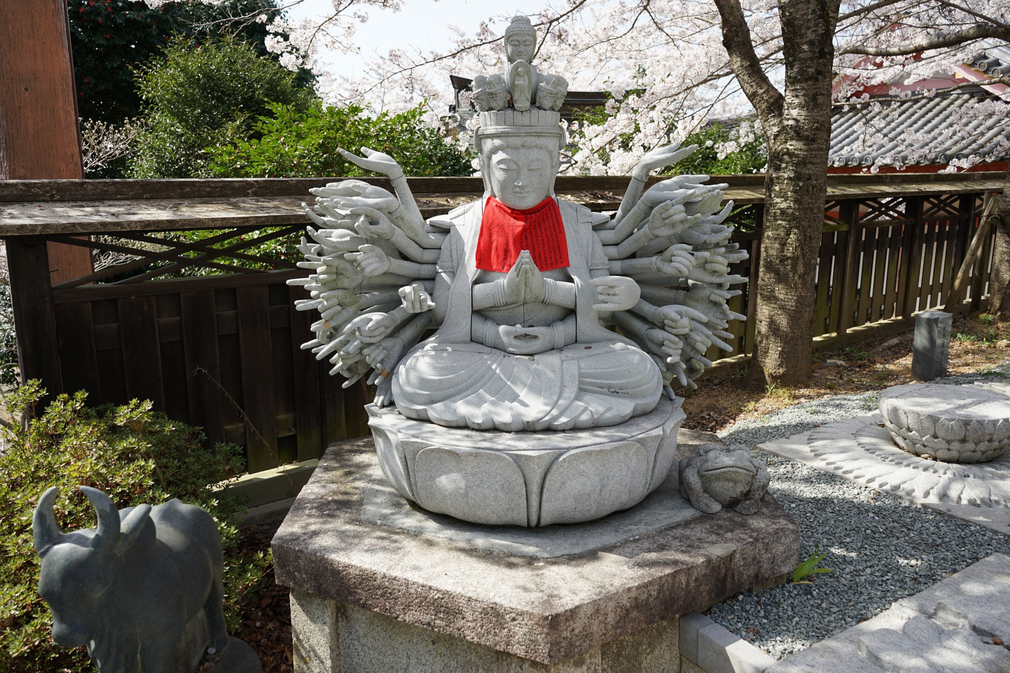 赤い前掛けをした壷阪寺の千手観音石像と桜